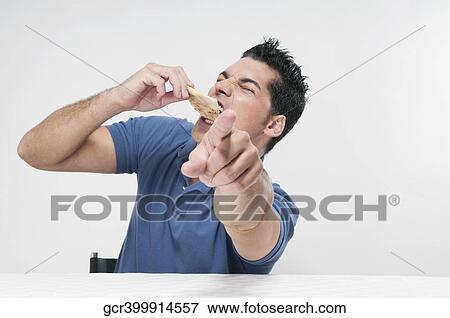 Stock Photo - Man eating pizza and pointing. Fotosearch