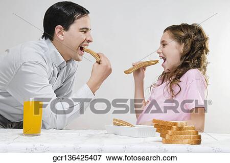 Stock Photo - Man eating slices of bread with his daughter . Fotosearch