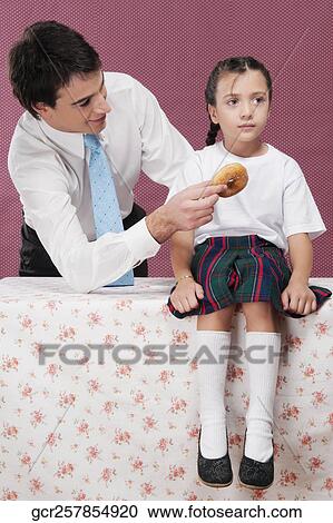 Man feeding donut to his daughter View Large Photo Image Stock Image - Man feeding donut to his daughter. Fotosearch