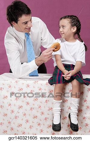 Stock Photography - Man feeding donut to his daughter. Fotosearch