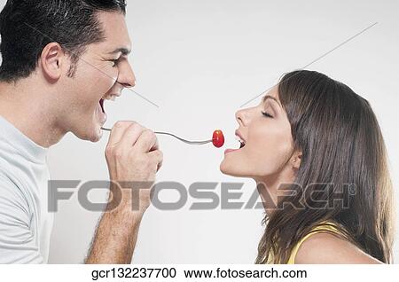 Man feeding woman a cherry tomato View Large Photo Image Stock Image - Man feeding woman a cherry tomato . Fotosearch