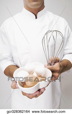 Man holding a bowl of eggs and a wire whisk View Large Photo Image Picture - Man holding a bowl of eggs and a wire whisk. Fotosearch