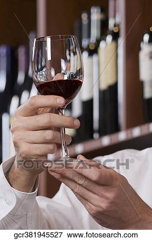 Man holding a wine glass in a bar View Large Photo Image Stock Photo - Man holding a wine glass in a bar. Fotosearch
