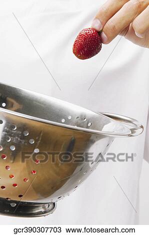 Stock Image - Man holding strawberries in a colander. Fotosearch