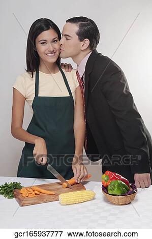 Man kissing a woman cutting vegetables View Large Photo Image Stock Photo - Man kissing a woman cutting vegetables. Fotosearch