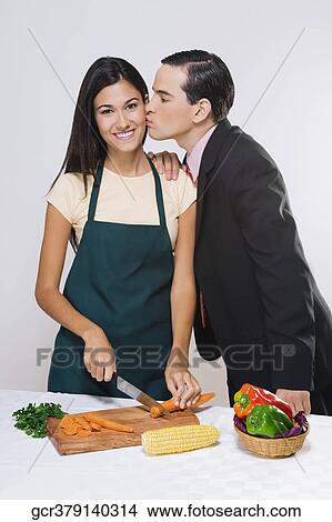 Man kissing his wife cutting vegetables View Large Photo Image Picture - Man kissing his wife cutting vegetables. Fotosearch