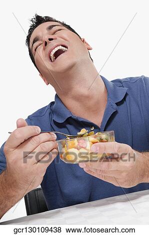 Man laughing while eating fruit salad View Large Photo Image Stock Photo - Man laughing while eating fruit salad. Fotosearch