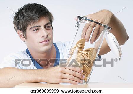 Stock Photo - Man reaching into a jar of cookies. Fotosearch