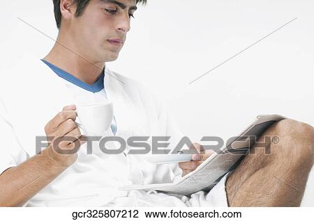 Man reading a newspaper with a cup of coffee View Large Photo Image Stock Image - Man reading a newspaper with a cup of coffee. Fotosearch