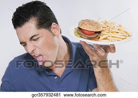 Man retching at a plate of hamburger and fries View Large Photo Image Stock Image - Man retching at a plate of hamburger and fries. Fotosearch