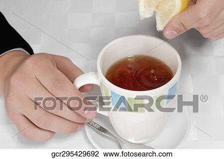 Man squeezing lemon into tea View Large Photo Image Stock Image - Man squeezing lemon into tea. Fotosearch