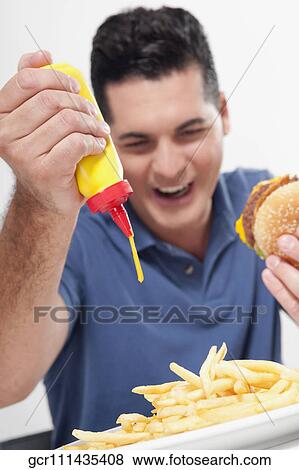 Man squeezing mustard on fries View Large Photo Image Stock Photo - Man squeezing mustard on fries. Fotosearch