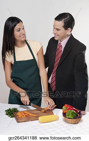 Man standing beside a woman cutting vegetables View Large Photo Image Stock Photo - Man standing beside a woman cutting vegetables. Fotosearch