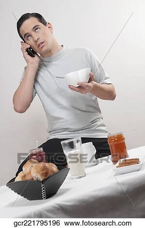 Stock Photograph - Man talking on a mobile phone at breakfast. Fotosearch
