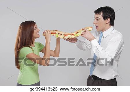 Man with his wife eating a hot dog View Large Photo Image Stock Image - Man with his wife eating a hot dog. Fotosearch