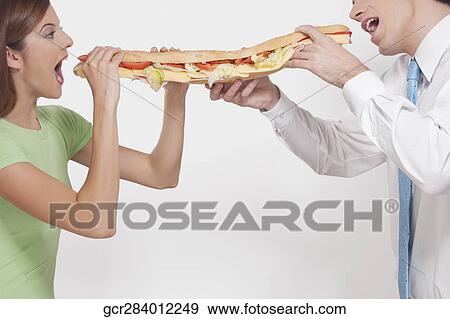 Man with his wife eating a hot dog View Large Photo Image Stock Photo - Man with his wife eating a hot dog. Fotosearch