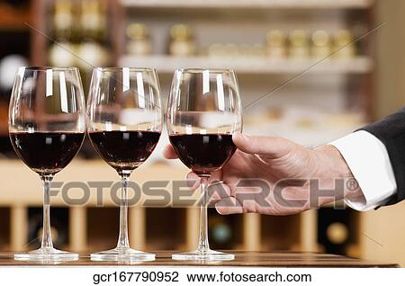 Man's hand holding a glass of wine in a bar View Large Photo Image Stock Image - Man's hand holding a glass of wine in a bar. Fotosearch