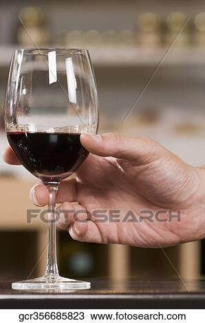 Man's hand holding a glass of wine in a bar View Large Photo Image Stock Image - Man's hand holding a glass of wine in a bar. Fotosearch