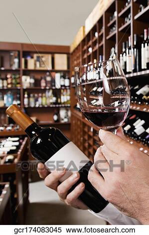 Man's hand holding a wine glass and a wine bottle View Large Photo Image Stock Photography - Man's hand holding a wine glass and a wine bottle. Fotosearch