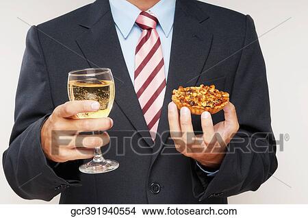 Mid section view of a businessman holding a glass of white wine and a tart View Large Photo Image Picture - Mid section view of a businessman holding a glass of white wine and a tart. Fotosearch