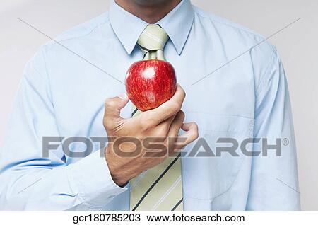 Mid section view of a businessman holding a red apple View Large Photo Image Stock Image - Mid section view of a businessman holding a red apple. Fotosearch