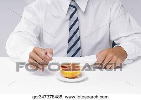 Mid section view of a businessman eating a grapefruit with a spoon View Large Photo Image Stock Photography - Mid section view of a businessman eating a grapefruit with a spoon. Fotosearch