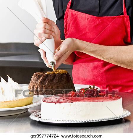 Mid section view of a female chef icing a cake View Large Photo Image Picture - Mid section view of a female chef icing a cake. Fotosearch