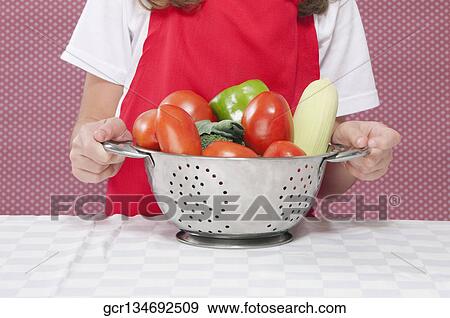 Mid section view of a girl holding raw vegetable in a colander View Large Photo Image Stock Photo - Mid section view of a girl holding raw vegetable in a colander. Fotosearch