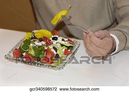 Stock Image - Mid section view of a man eating salad. Fotosearch