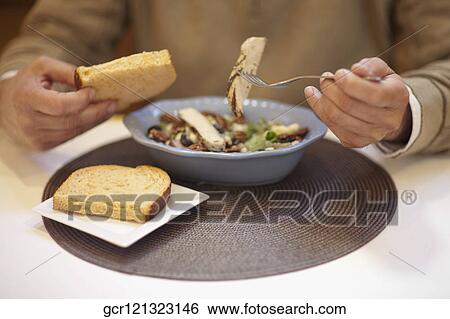 Mid section view of a man eating salad with bread View Large Photo Image Stock Photograph - Mid section view of a man eating salad with bread. Fotosearch