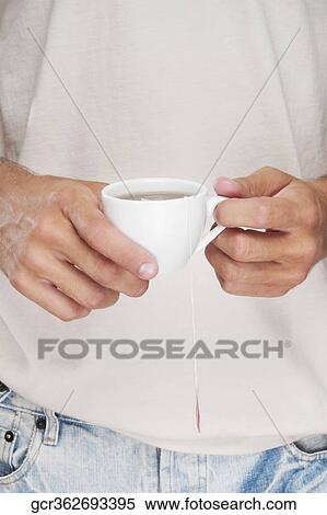 Mid section view of a man holding a cup of coffee View Large Photo Image Stock Photography - Mid section view of a man holding a cup of coffee. Fotosearch