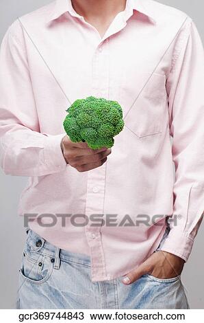Mid section view of a man holding a broccoli View Large Photo Image Stock Image - Mid section view of a man holding a broccoli. Fotosearch