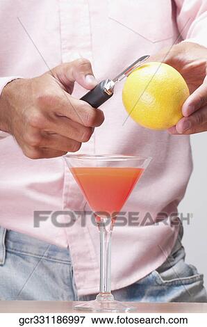 Stock Photo - Mid section view of a man peeling a lemon over a cocktail. Fotosearch