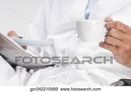 Mid section view of a man reading a newspaper with a cup of coffee View Large Photo Image Stock Photo - Mid section view of a man reading a newspaper with a cup of coffee. Fotosearch