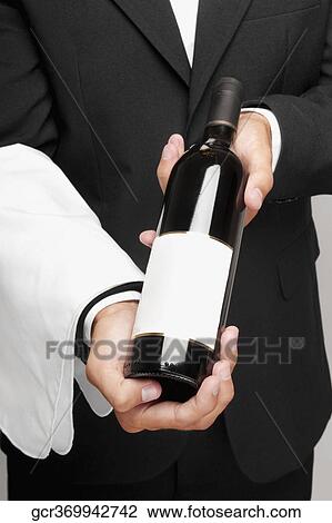 Mid section view of a waiter holding a bottle of wine View Large Photo Image Stock Image - Mid section view of a waiter holding a bottle of wine. Fotosearch