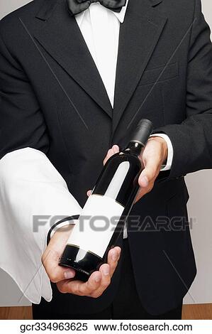 Mid section view of a waiter holding a bottle of wine View Large Photo Image Stock Photography - Mid section view of a waiter holding a bottle of wine. Fotosearch
