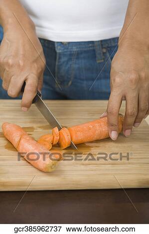 Mid section view of a woman cutting a carrot View Large Photo Image Stock Photo - Mid section view of a woman cutting a carrot. Fotosearch