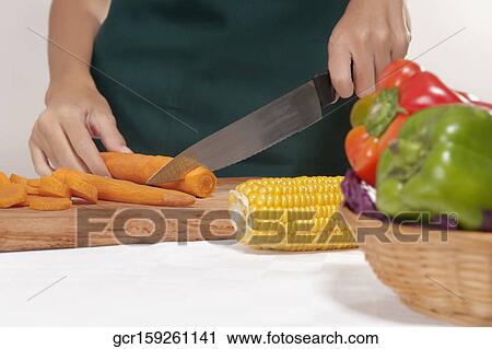 Mid section view of a woman cutting vegetables View Large Photo Image Stock Image - Mid section view of a woman cutting vegetables. Fotosearch