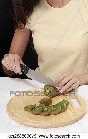 Mid section view of a woman cutting kiwi fruit View Large Photo Image Stock Photo - Mid section view of a woman cutting kiwi fruit. Fotosearch