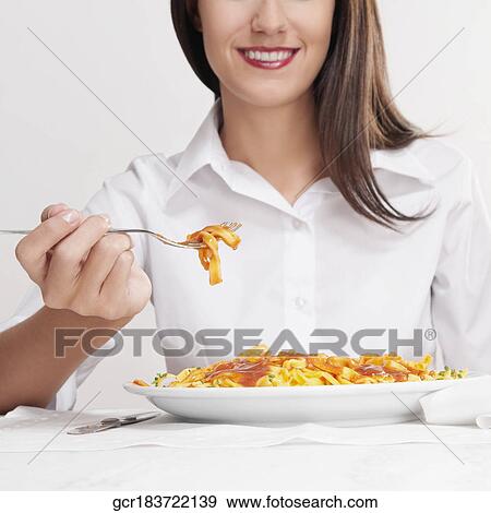 Stock Photo - Mid section view of a woman eating pasta. Fotosearch