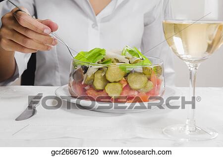 Stock Image - Mid section view of a woman eating salad. Fotosearch