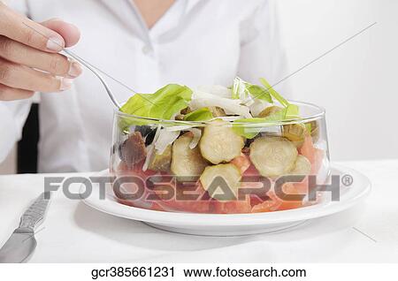 Mid section view of a woman eating salad View Large Photo Image Stock Image - Mid section view of a woman eating salad. Fotosearch