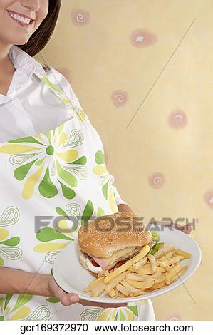 Mid section view of a woman holding burger and French fries on a plate View Large Photo Image Stock Image - Mid section view of a woman holding burger and French fries on a plate. Fotosearch