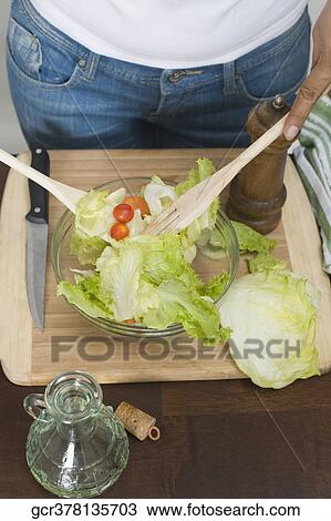 Stock Image - Mid section view of a woman tossing salad. Fotosearch