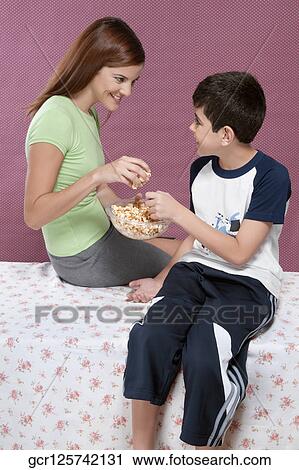 Mother with her son sharing a bowl of popcorn View Large Photo Image Stock Image - Mother with her son sharing a bowl of popcorn. Fotosearch