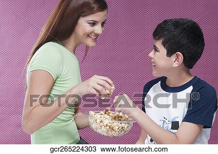 Mother with her son sharing a bowl of popcorn View Large Photo Image Stock Image - Mother with her son sharing a bowl of popcorn. Fotosearch