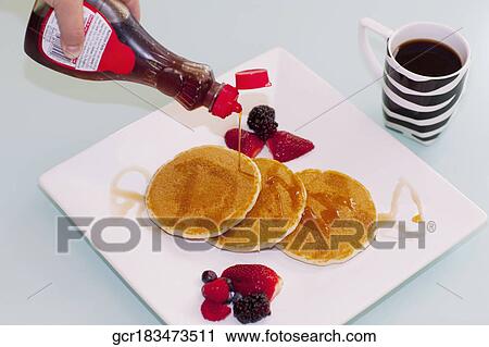 Person's hand pouring syrup on pancakes View Large Photo Image Stock Image - Person's hand pouring syrup on pancakes. Fotosearch