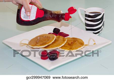 Person's hand pouring syrup on pancakes View Large Photo Image Stock Photo - Person's hand pouring syrup on pancakes. Fotosearch