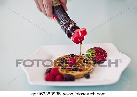 Person's hand pouring syrup on waffles View Large Photo Image Stock Photograph - Person's hand pouring syrup on waffles. Fotosearch