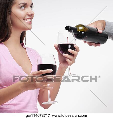 Stock Photo - Person's hand pouring wine into a glass held by a woman. Fotosearch